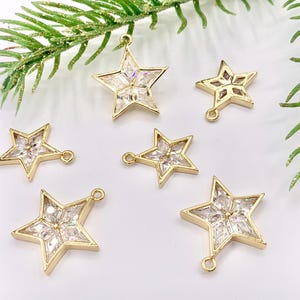 May include: A set of six gold-tone star-shaped charms with clear crystal accents. The charms have a loop at the top for attaching to jewelry or other crafts.