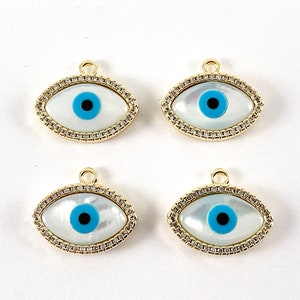 May include: Four gold-toned evil eye charms with white mother of pearl and blue and black enamel accents. The charms are oval shaped and have a small loop at the top for attaching to jewelry.