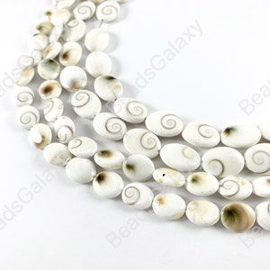 May include: A strand of white oval shell beads with brown and green swirls. The beads are strung on a white cord.