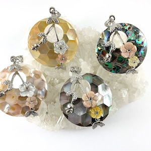May include: Four round pendants made of iridescent abalone shell with silver floral accents. Each pendant features a different color combination of abalone shell.