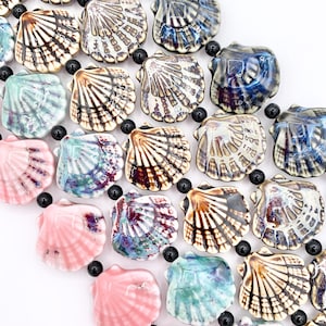 May include: A collection of ceramic scallop shell beads in various glossy colors including pink, turquoise, blue, and brown, arranged in a grid pattern and separated by small, round, black spacer beads, creating a textured, multi-colored surface.