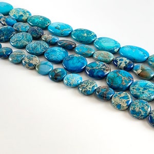 May include: A strand of blue and white oval-shaped gemstone beads. The beads are arranged in rows, with the largest beads at the top and the smallest beads at the bottom.