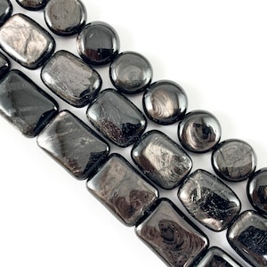 May include: Black obsidian beads with a silver sheen, some are round and some are rectangular. The beads are strung together on a string.