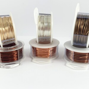 May include: Three spools of wire in different colors: gold, silver, and copper. The wire is wound around a clear plastic spool with a white plastic handle.