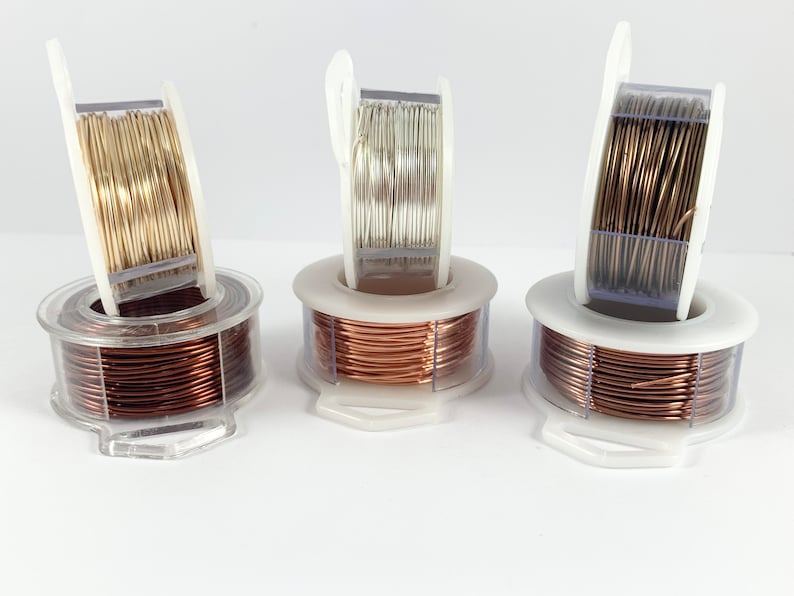 May include: Three spools of wire in different colors: gold, silver, and copper. The wire is wound around a clear plastic spool with a white plastic handle.