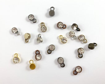 May include: Assortment of small, clear rhinestone charms with metal loops. The charms are in various metal finishes, including gold, silver, and bronze.