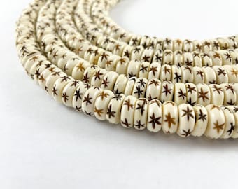 May include: A strand of white beads with brown star-shaped patterns. The beads are round and have a smooth, polished finish.