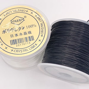 May include: Two spools of black elastic string, one with a white label that reads "ボリウレタン 100% 日本 水晶线" and "CRYSTAL LINE" in English and Japanese.