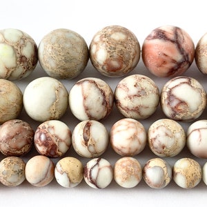 May include: A strand of round, brown, white, and pink jasper beads. The beads have a mottled, marbled appearance.