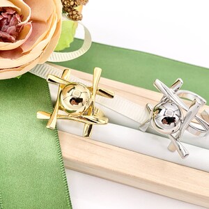 May include: Two gold and silver rings with a sphere design. The rings are displayed on a wooden box with a green ribbon.
