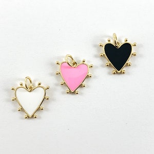 Può includere: Tre ciondoli a forma di cuore con montatura dorata e piccole perline dorate sui bordi. I cuori sono riempiti di smalto bianco, rosa e nero. Ogni ciondolo ha un piccolo anello nella parte superiore per appenderlo.