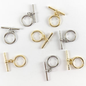 May include: Eight silver and gold toggle clasps for jewelry making. The clasps have a round ring and a bar with a small loop on one end.