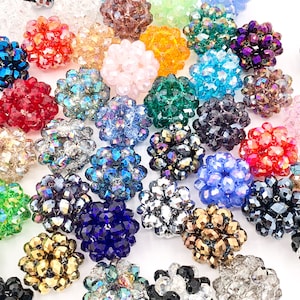 May include: Assortment of colorful crystal beads in various shapes and sizes. The beads are clustered together and appear to be made of glass or crystal.