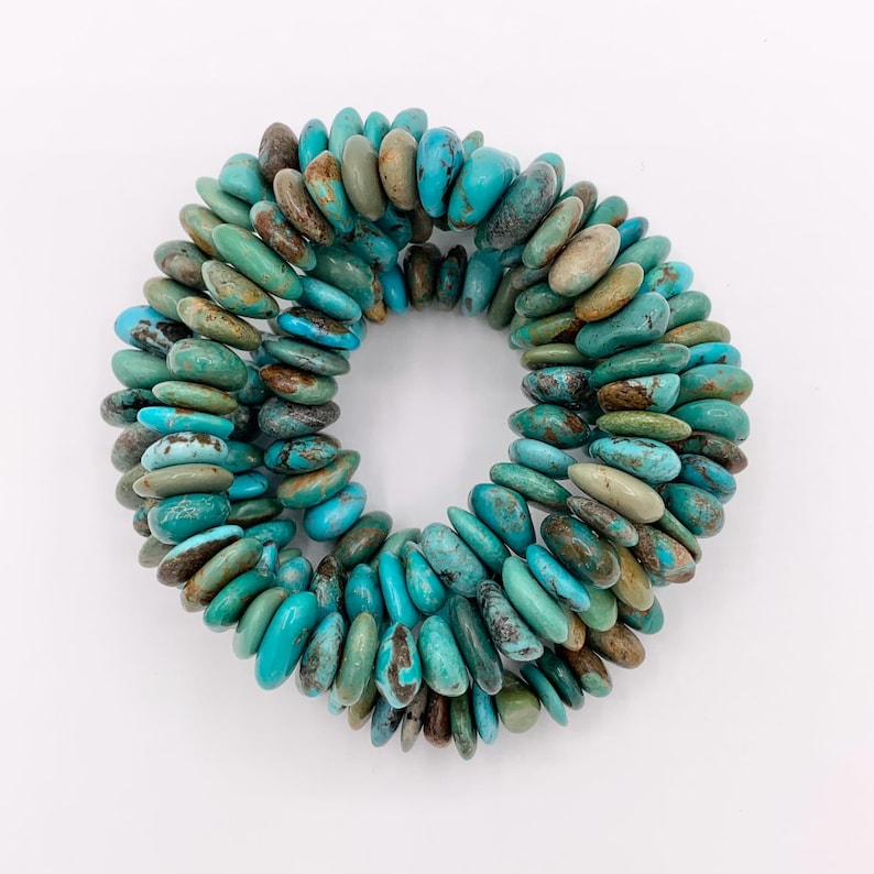 May include: A turquoise stone bracelet with a circular design. The bracelet is made of oval-shaped stones in shades of turquoise, blue, and brown. The stones are arranged in a circular pattern, creating a unique and eye-catching accessory.