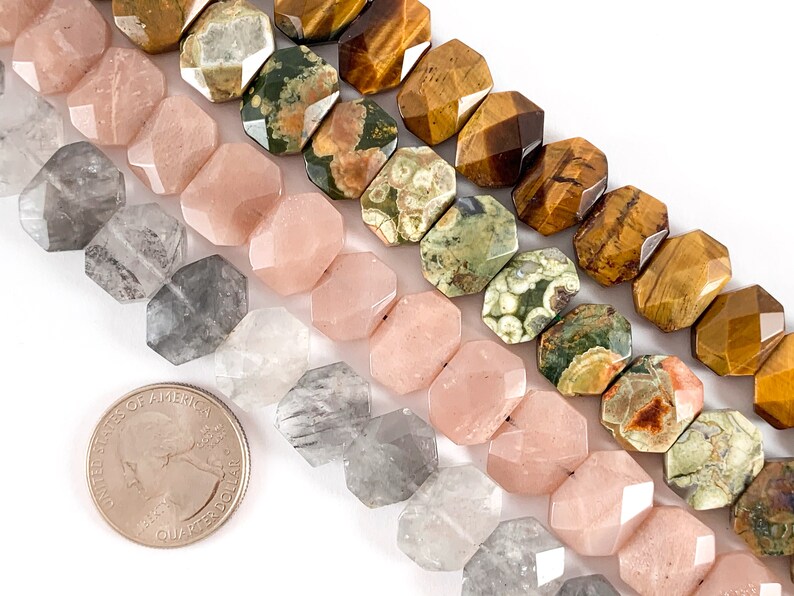 May include: A close-up of four strands of gemstone beads. The top strand is brown tiger's eye, the next is green and white ocean jasper, the third is pink rose quartz, and the bottom is clear and gray smoky quartz. The beads are faceted and have a hexagonal shape.