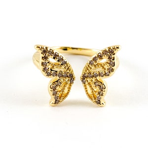 May include: A gold butterfly ring with clear rhinestones. The ring is open in the back and has a delicate design.