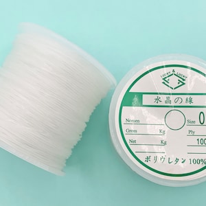 May include: A spool of white elastic thread labeled "LUCKY & LUCKY 水晶の線 Size 0.8 m/m Ply 100m ボリウレタン 100%"