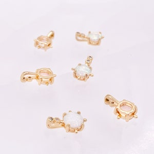 May include: Five gold-tone pendants with white opal stones. Each pendant has a bail for attaching to a chain or cord.