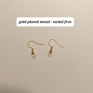 May include: Two gold-plated metal earring hooks, nickel-free, are displayed against a neutral background. The hooks have a simple, elegant design, with a curved wire for the ear and a small loop at the bottom. The text "gold plated metal - nickel free" is above the hooks.