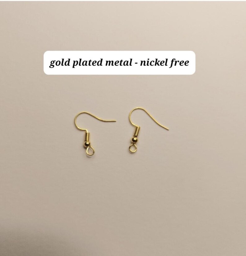 May include: Two gold-plated metal earring hooks, nickel-free, are displayed against a neutral background. The hooks have a simple, elegant design, with a curved wire for the ear and a small loop at the bottom. The text "gold plated metal - nickel free" is above the hooks.