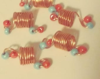 Peut inclure: Six spirales pour cheveux en cuivre avec des perles bleues et orange. Les spirales sont faites de fil métallique et sont conçues pour aider à maintenir les cheveux en place.