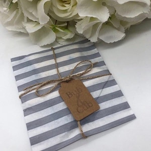 May include: A grey and white striped tissue paper gift bag with a brown tag that says "Bub & Cub". The bag is tied with twine.