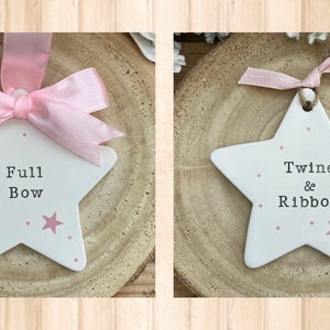 May include: Two white ceramic star ornaments with pink polka dots and a pink star. One ornament says "Full Bow" and the other says "Twine & Ribbon".