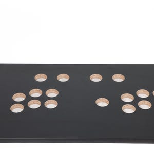 May include: Black control panel with multiple round holes cut out for buttons and joysticks. The panel is made of wood and has a smooth, matte finish.