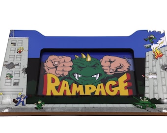 Könnte beinhalten: Ein blauer und gelber Arcade-Schrank mit einem grünen Monster und dem Wort "RAMPAGE" in gelben Buchstaben. Das Monster ist mit erhobenen Fäusten und einem bedrohlichen Ausdruck dargestellt. Der Schrank ist mit Bildern von Gebäuden und Menschen verziert.