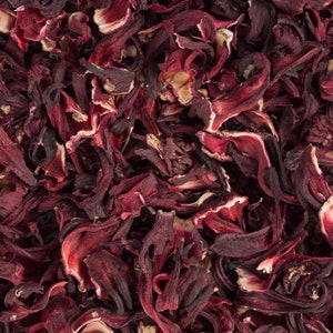 May include: A close-up shot of dried hibiscus flowers, displaying deep red petals with pale edges. The petals are curled and layered, creating a textured appearance. The image highlights the natural, organic form of the dried flowers, often used for herbal teas.