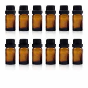 May include: Twelve amber glass essential oil bottles with black caps are arranged in three rows of four. The bottles are small, cylindrical, and filled with a liquid. The caps are black and screw-on. The background is white.