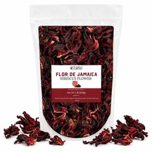 May include: A transparent bag containing dried hibiscus flowers, with some scattered around the base. The label on the bag reads "FLOR DE JAMAICA HIBISCUS FLOWER" and states the net weight as 454g. The flowers are a rich, dark red colour.