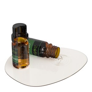 May include: Two amber glass bottles with dropper tops, one upright and one tipped over, spilling a clear liquid onto a white surface. The bottles are labeled "ZavBe" and "uBe" with green text. The upright bottle is labeled "ORGANO 1/2 FL OZ".