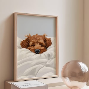 Pode incluir: Uma ilustração emoldurada de um cão castanho e branco a dormir num travesseiro branco. O cão tem os olhos fechados e o nariz visível. A moldura é de madeira clara.