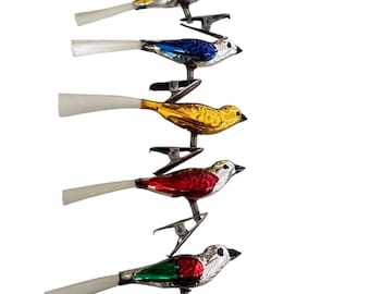 Può includere: Una collezione di ornamenti natalizi vintage a forma di uccello. Ogni uccello ha una clip per il fissaggio ed è dipinto in vari colori, tra cui rosso, oro, blu e verde. Gli uccelli hanno piume della coda bianche e becchi neri.
