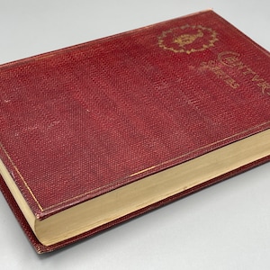 Puede incluir: Un libro de tapa dura rojo con letras doradas en el lomo. El libro se titula "The Works of Charles Dickens".