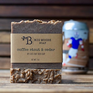 May include: A bar of brown coffee stout and cedar scented soap with a brown paper label that reads "Big Woods Soap, coffee stout & cedar, NY State Craft Beer Soap, Net Wt. 5 oz."