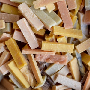 May include: A box filled with a variety of rectangular soap bars in different colors, including brown, beige, yellow, and green.