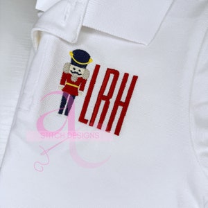 May include: White polo shirt with red embroidered letters "LRH" and a small embroidered nutcracker figure.