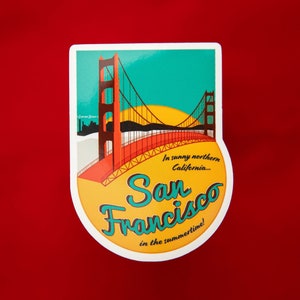 Sticker with a teal sky and yellow sun with the red Golden Gate Bridge. In teal script lettering it reads, San Francisco, and around it reads, In sunny northern California... in the summertime! Sticker rests on a red background.