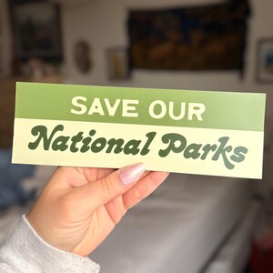 Green and beige bumper sticker that reads, Save Our National Parks