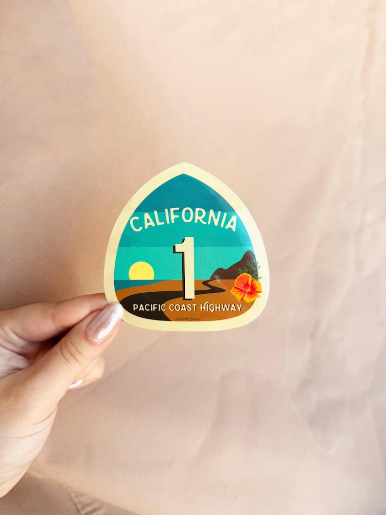 May include: A yellow and blue sticker with the text "California 1 Pacific Coast Highway". The sticker features a sunset scene with a palm tree and a road.