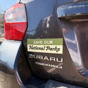 Green and beige bumper sticker that reads, Save Our National Parks
