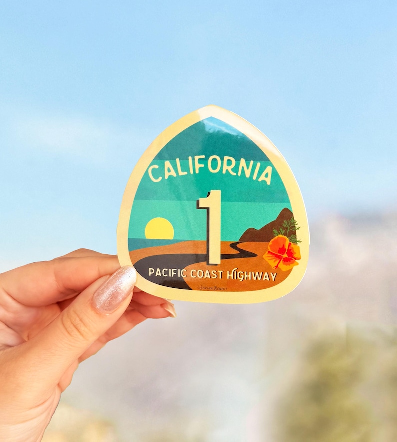May include: A yellow and blue sticker with the text "California 1 Pacific Coast Highway". The sticker features a sunset over a beach with a road winding through it.