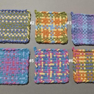 May include: Six colourful woven potholders in various patterns and colours, including blue, green, orange, purple, and pink. Each potholder has a loop for hanging. The potholders are numbered 1 to 6.