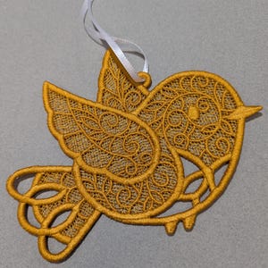 May include: A gold-colored bird-shaped ornament with intricate lace-like details. The ornament has a white ribbon attached for hanging.