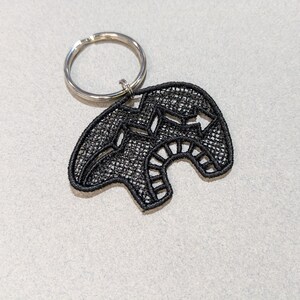 May include: Black embroidered bear keychain with a silver key ring.