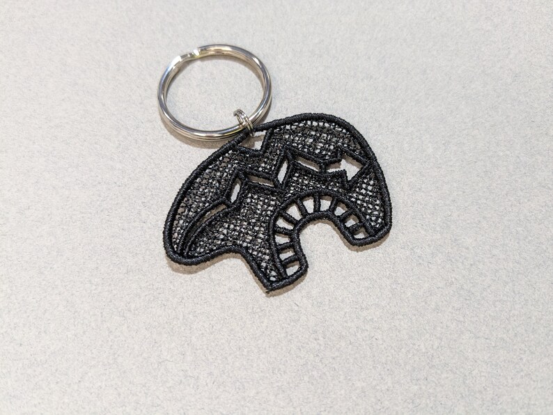 May include: Black embroidered bear keychain with a silver key ring.