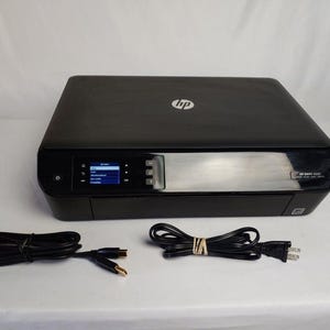 May include: Black HP ENVY 4500 series printer with a small LCD screen and silver accents. Includes a power cord and a USB cable. The HP logo is visible on the top of the printer.