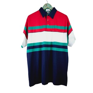 May include: A short-sleeved, multi-colored striped polo shirt with a button-down collar and a single button closure. The shirt has a red, green, white, and navy blue color scheme.